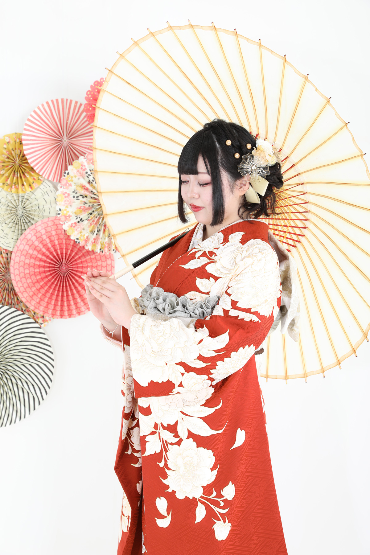 赤地に白い花柄の振袖と和傘のスタジオ写真